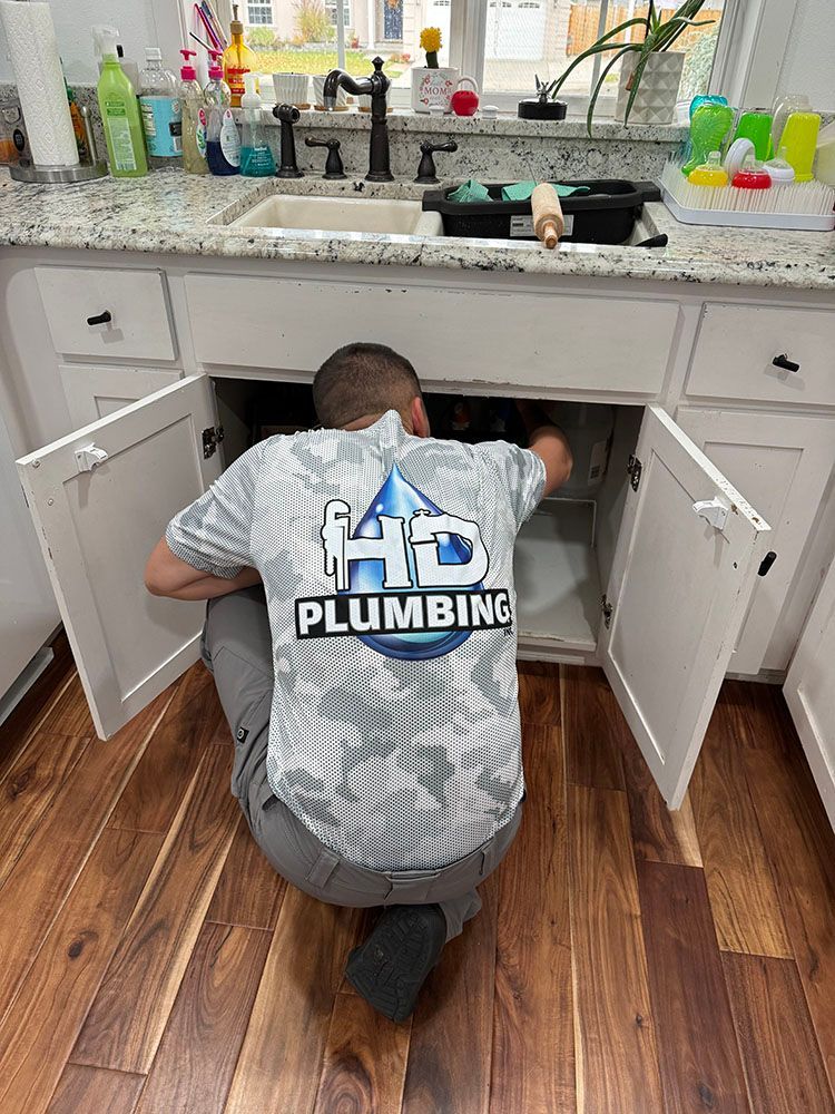 A man is kneeling under a sink in a kitchen.