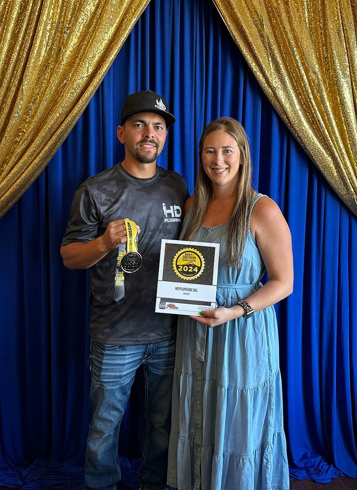 A man and a woman are posing for a picture in front of a blue curtain.