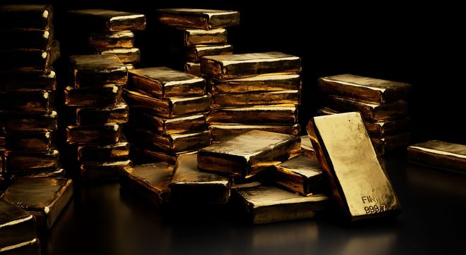 Stacks of gold bars and coins on a dark surface, lit with warm golden light.