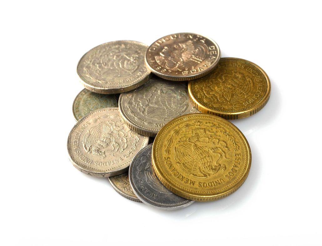 Assorted gold and silver coins piled together on a white background