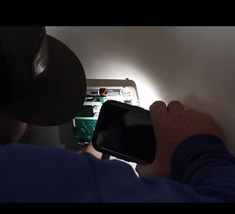 Person holding a phone while looking at a laptop screen in a dim room