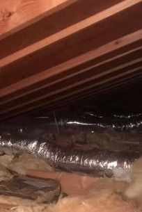 Insulated HVAC ductwork in an unfinished attic with exposed wooden rafters