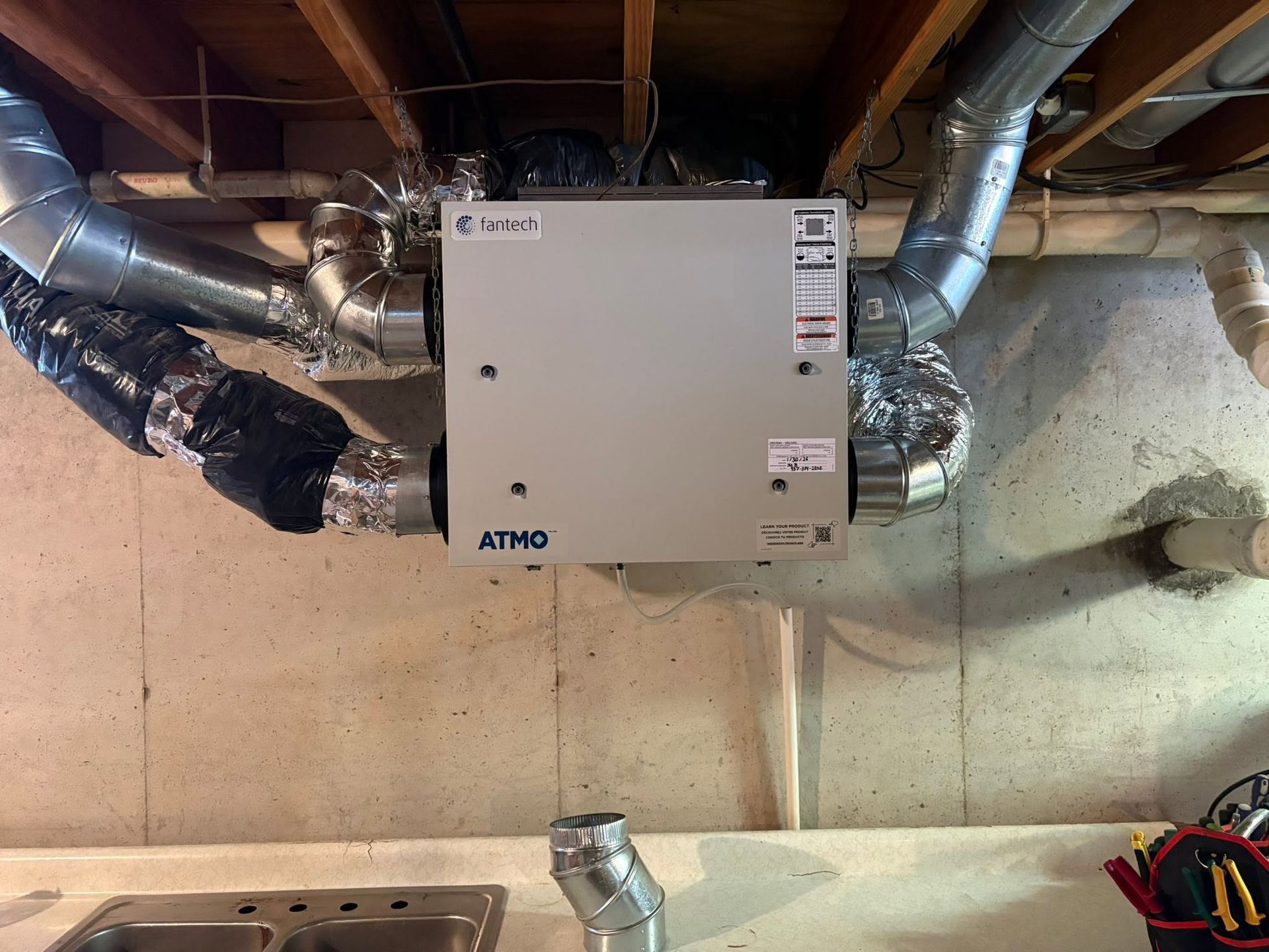 Basement utility room with a wall-mounted HVAC unit and exposed ductwork.