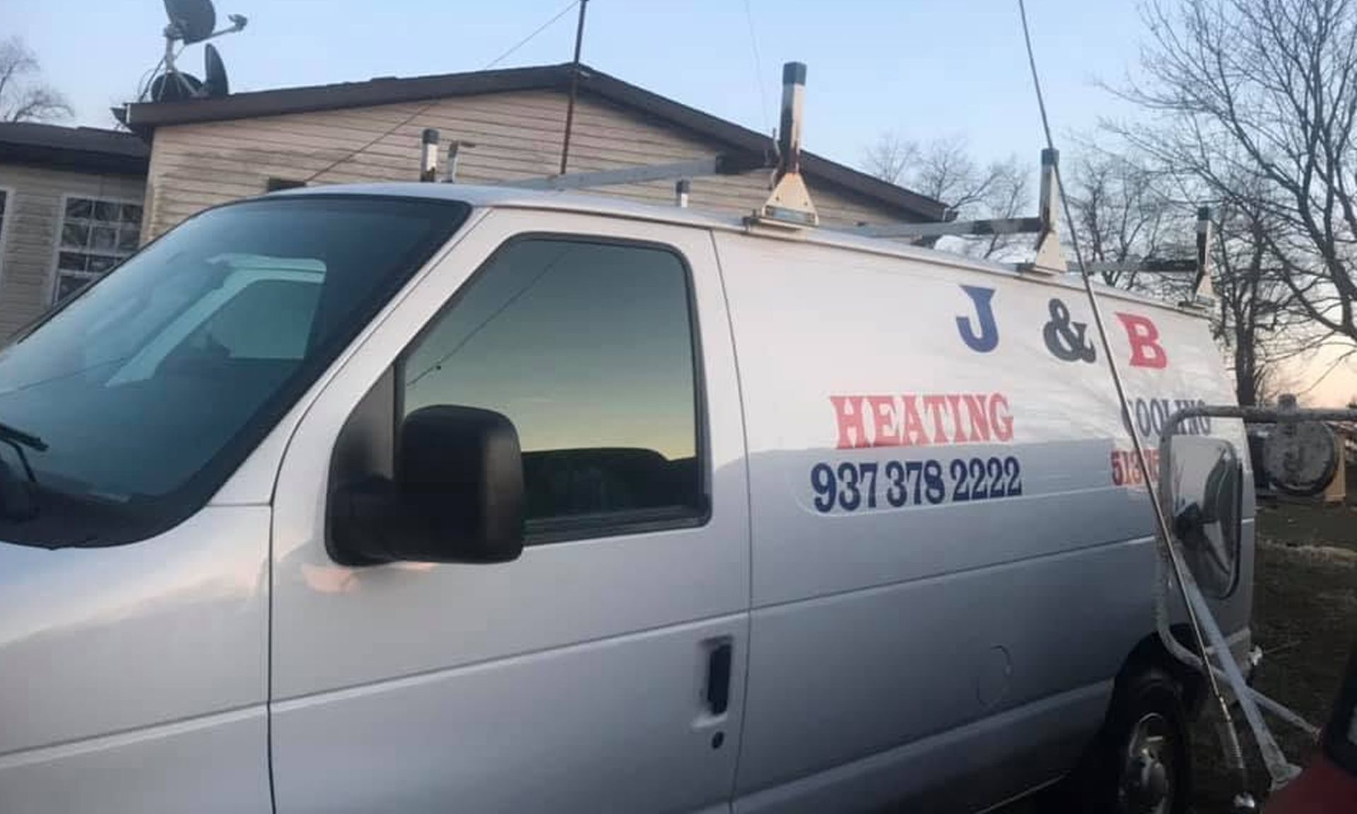 White heating service van with “A&B Heating” text parked outdoors near a house