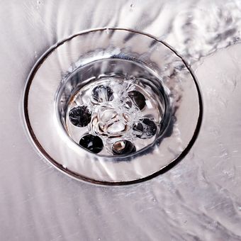 A close up of a sink drain with water running down it.