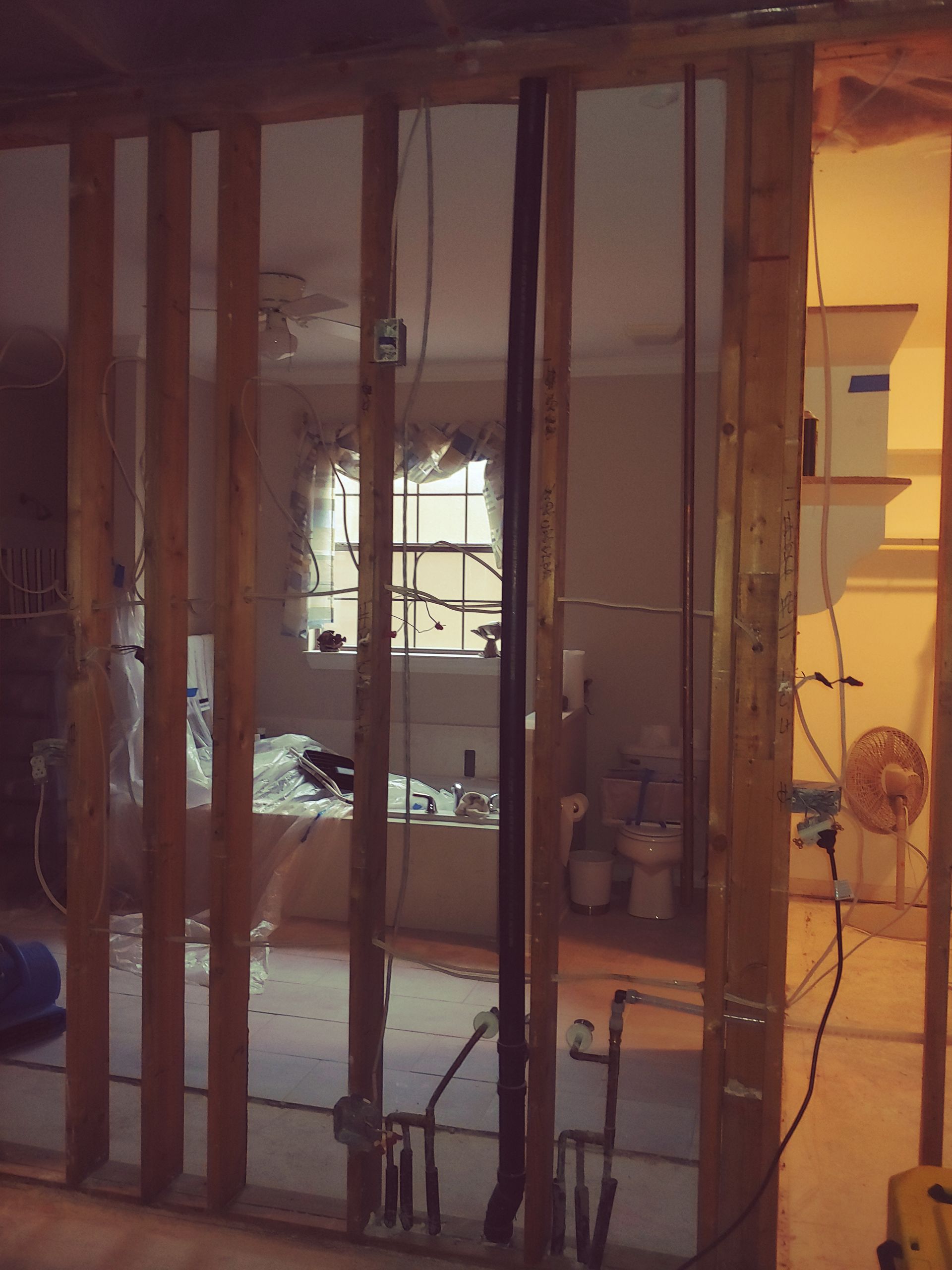 Interior wall studs with view into bathroom during renovation.