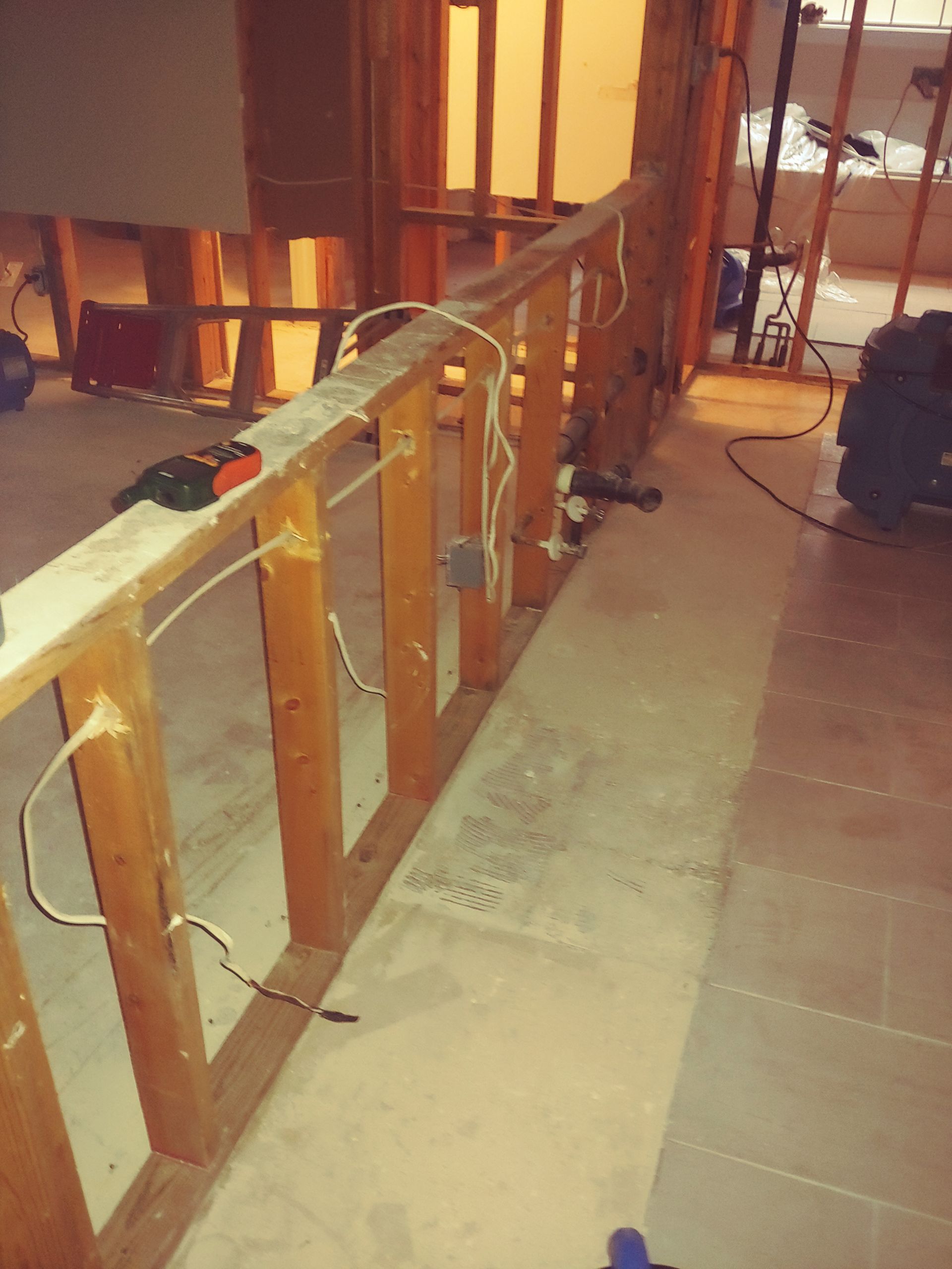 Construction site with wooden framing, electrical wiring, and concrete flooring.