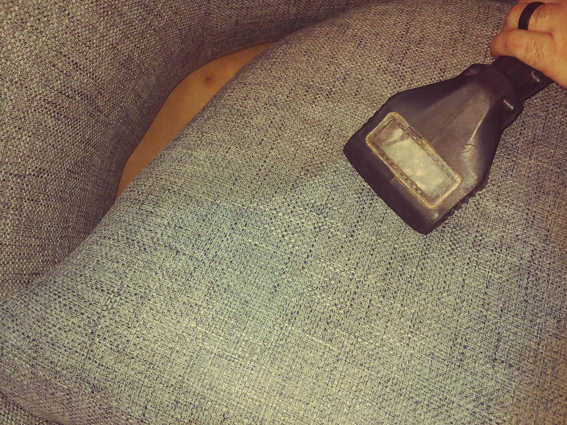 Person using a handheld carpet cleaner on a light blue carpet, revealing a yellow underlayer.