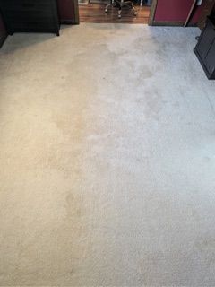 Beige carpeted room with darker patches, leading to a doorway.