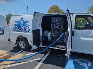 White All-Star carpet cleaning van with doors open, hoses out. Parked in a spot, blue wheelchair symbol.