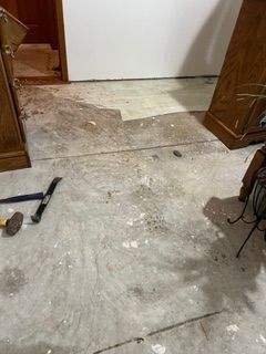 Concrete floor with debris and tools, cabinets flanking the doorway.