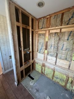 Bathroom under construction; exposed wall studs, insulation, and plumbing.