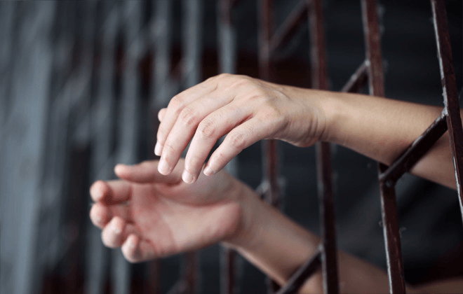 person-arms-through-jail-bars