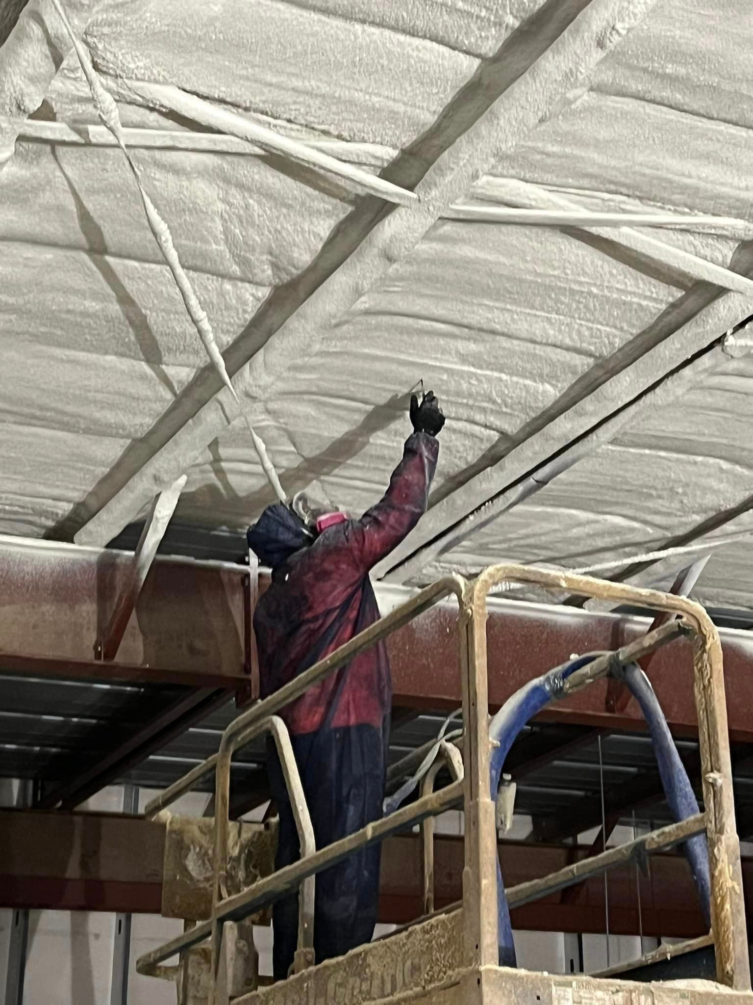 a man is spraying foam on the ceiling of a building .