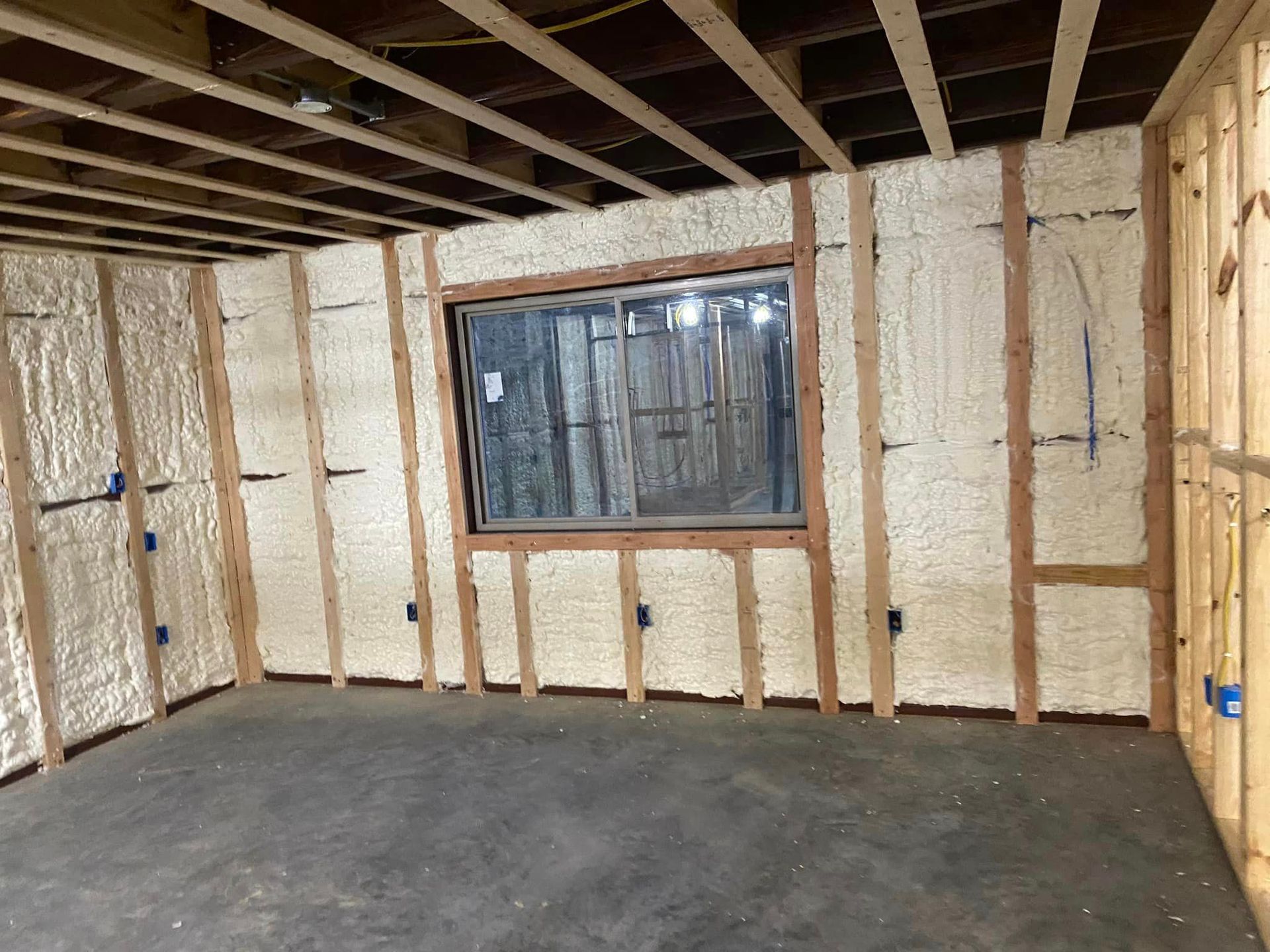 a room with a window and walls covered in spray foam .