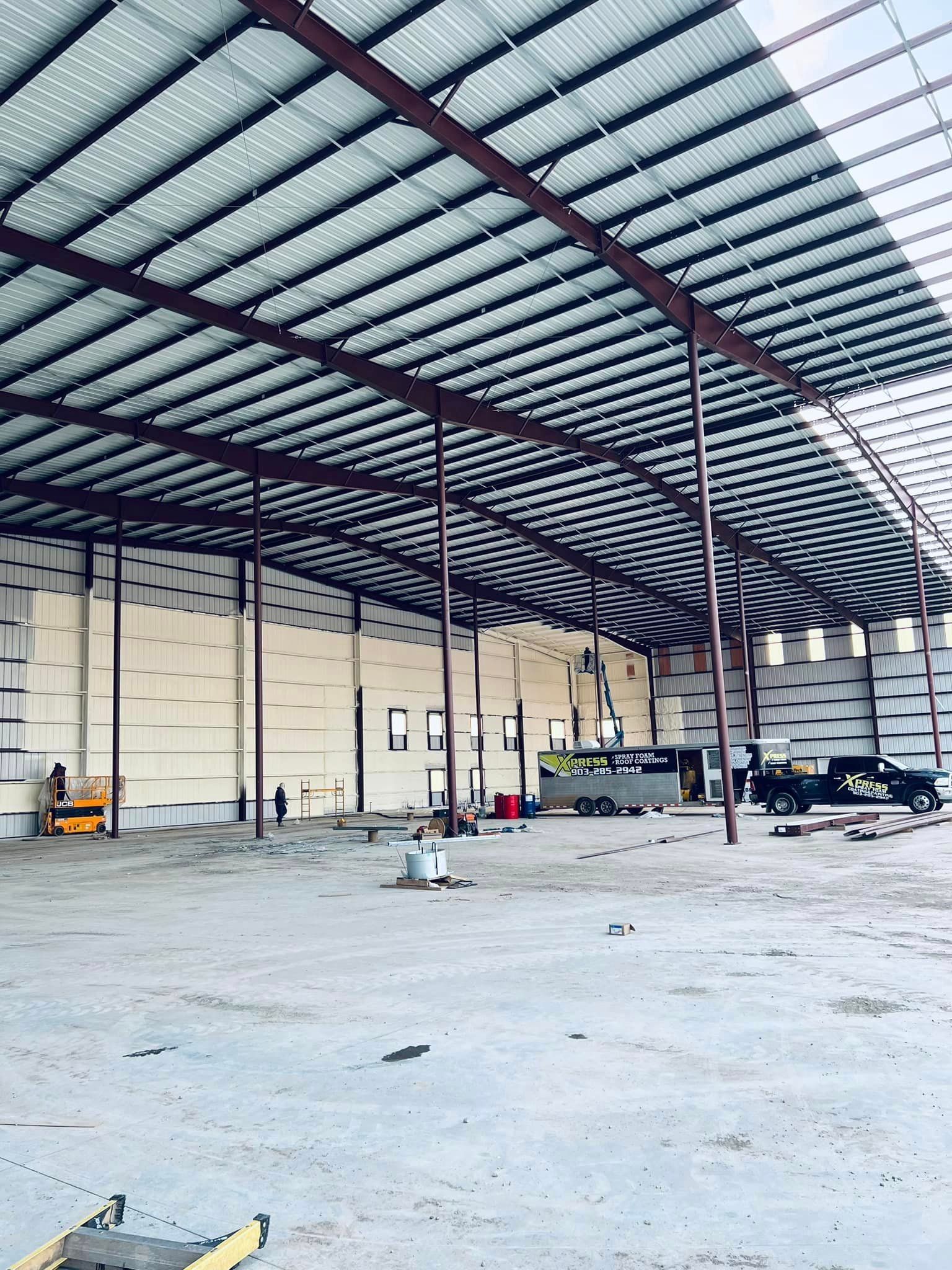 a large empty warehouse with a roof that is being built .