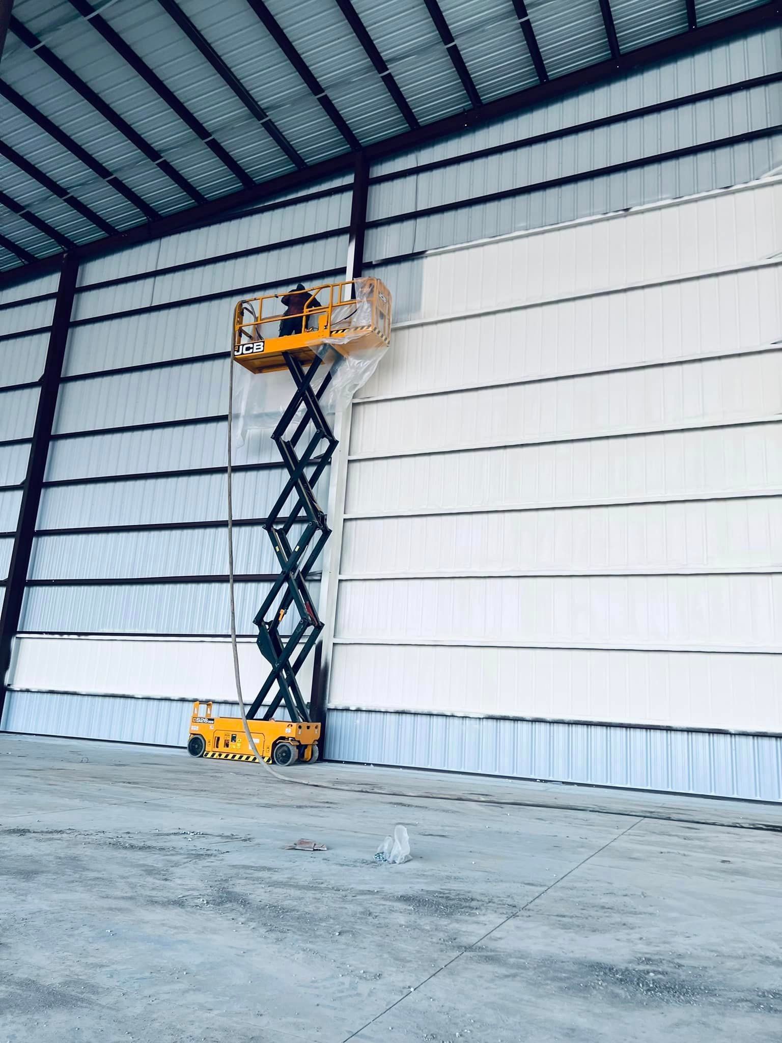 a man is standing on a scissor lift in a warehouse .