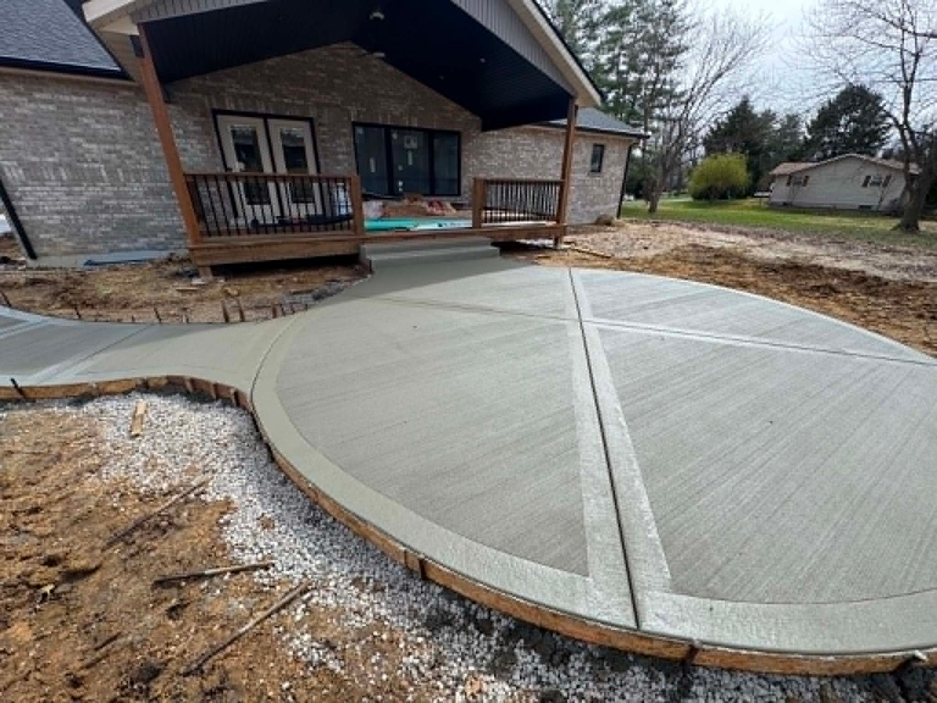New concrete patio beside a house with curved edges and a covered porch