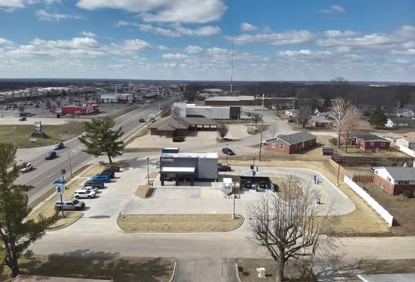 Aerial view of a gas station and parking lot beside a road under a partly cloudy sky