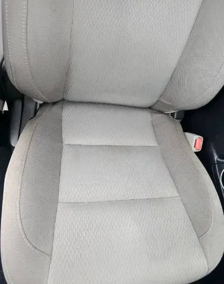 A light gray fabric vehicle bucket seat with darker gray side bolsters.
