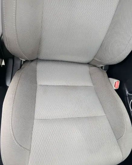 Tan car seat with some stains on the fabric.