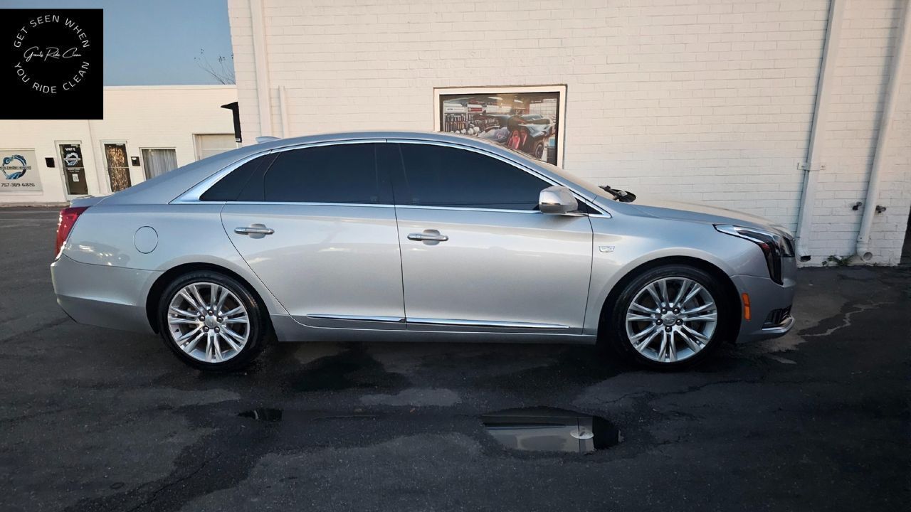 Silver Cadillac sedan parked outside a building with tinted windows.