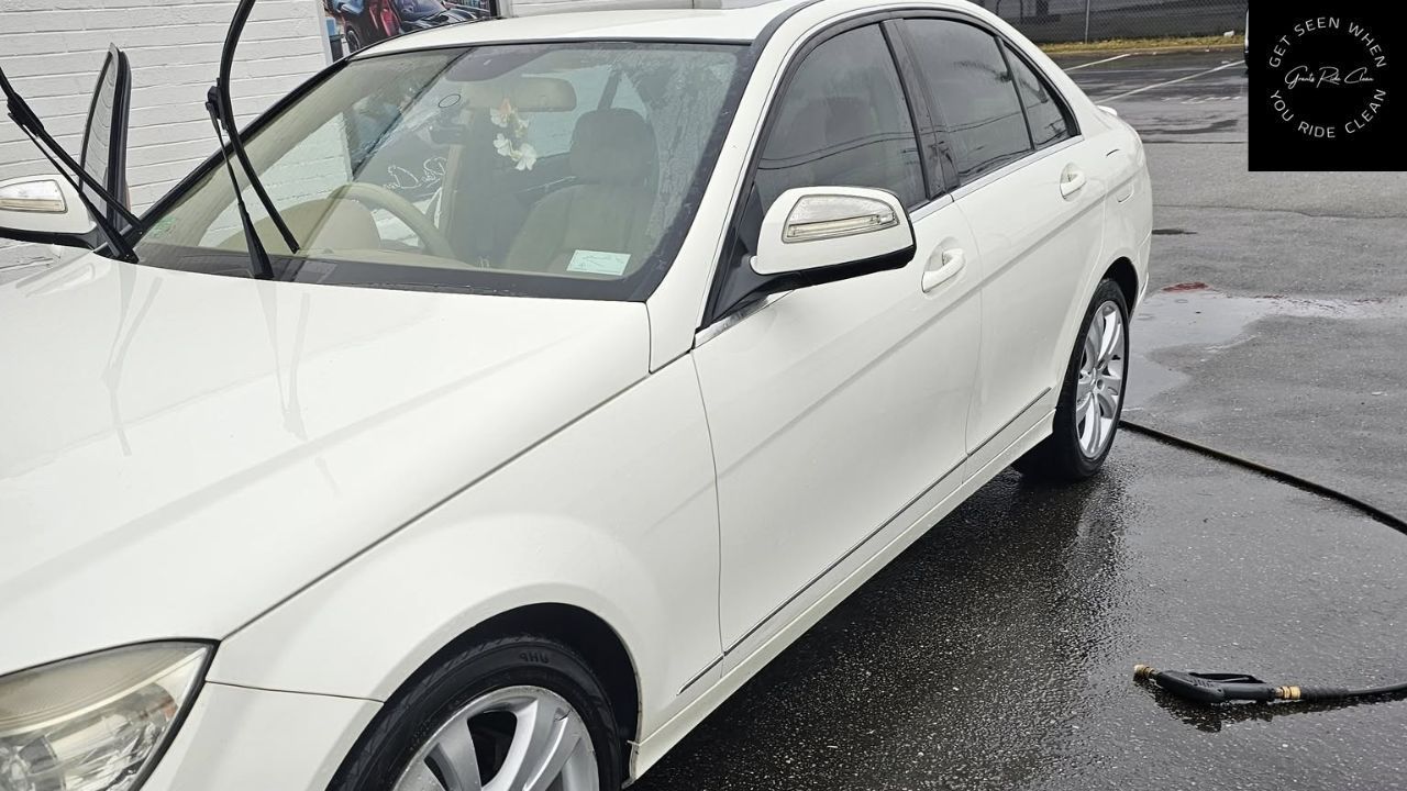 White sedan being washed with water at a car wash.