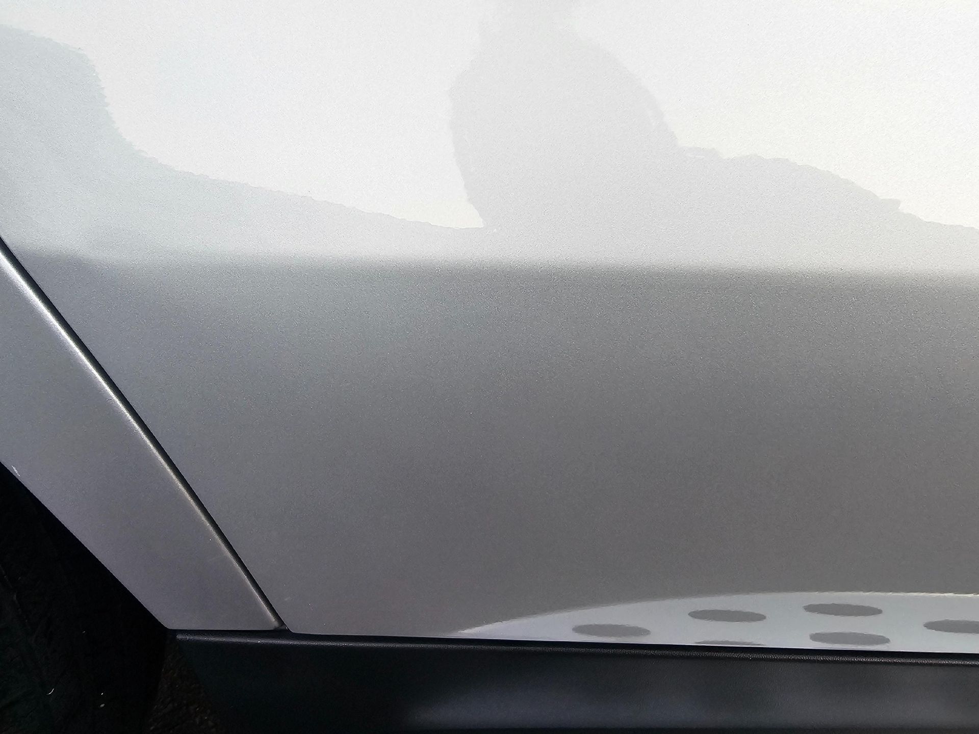 Silver car door and side panel with black trim.