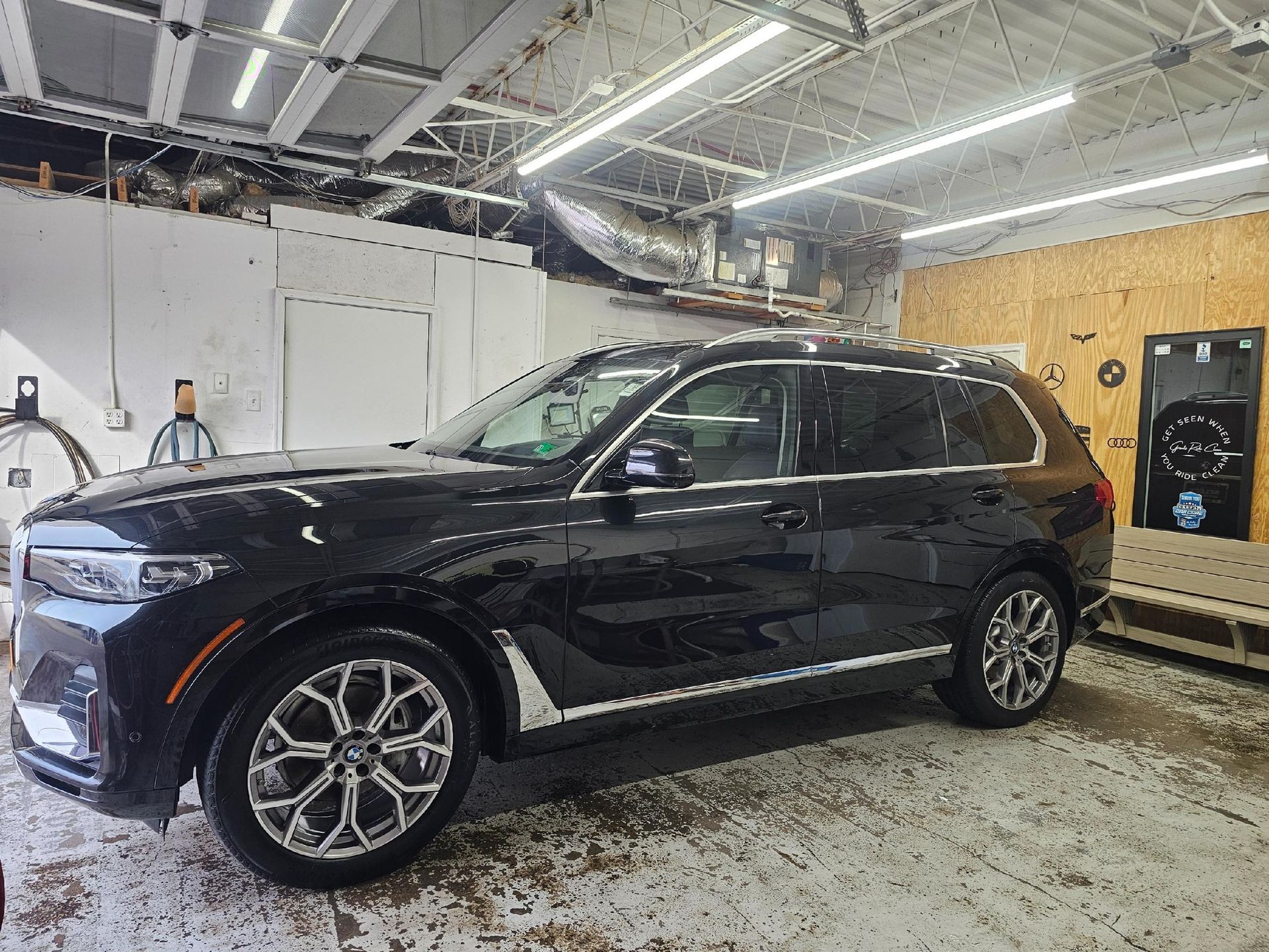 Black SUV parked inside a garage; person in background.