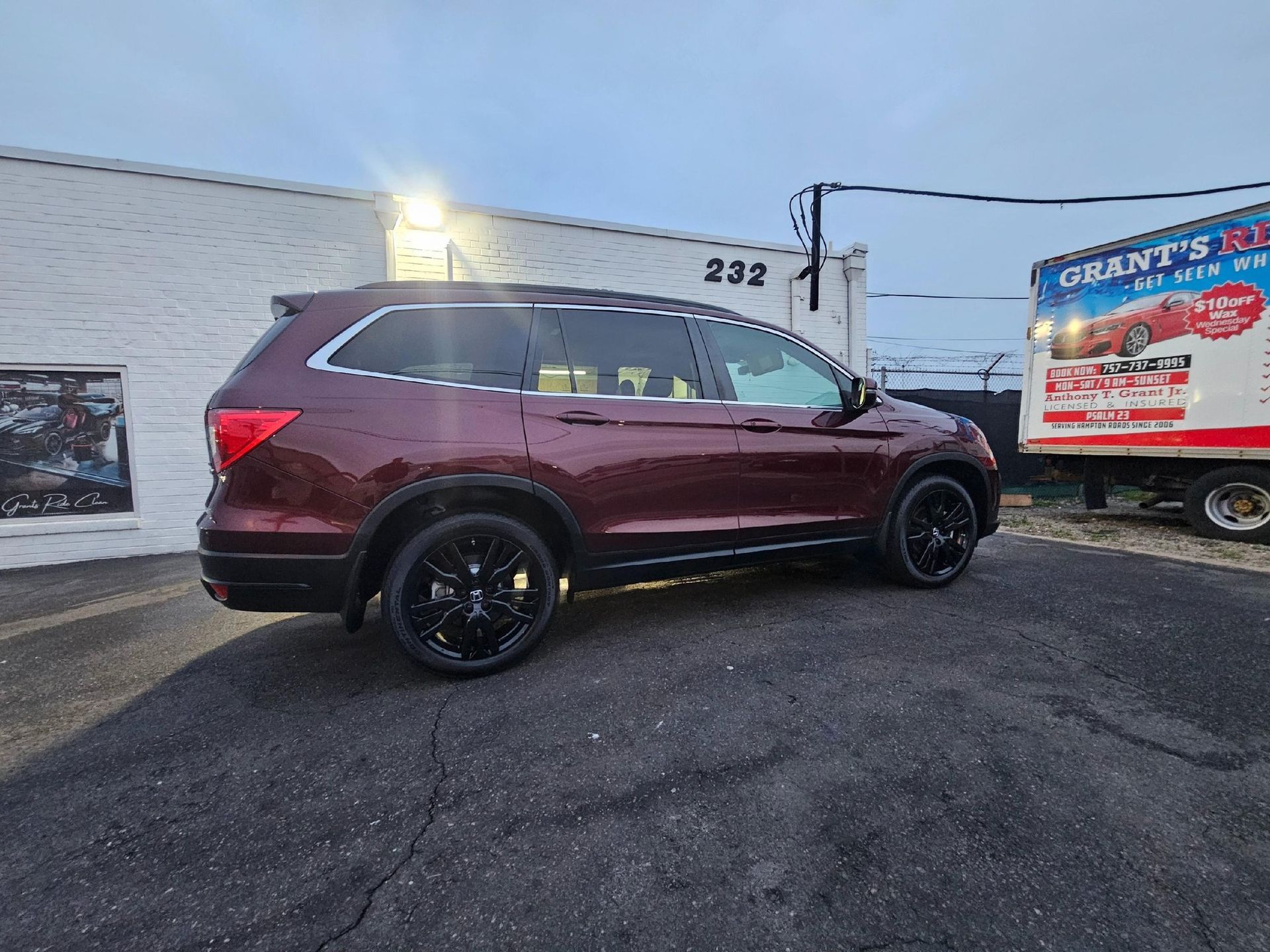 Burgundy SUV parked outside a building with the number 232, black wheels.