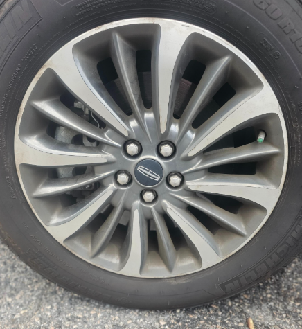 Close-up of a silver and gray car wheel with a Lincoln logo on a black tire.