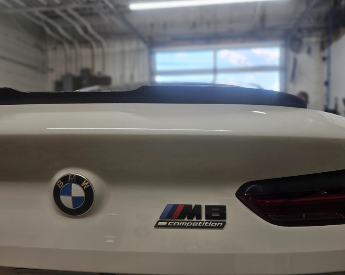 White BMW M8 Competition trunk with BMW emblem and badges.