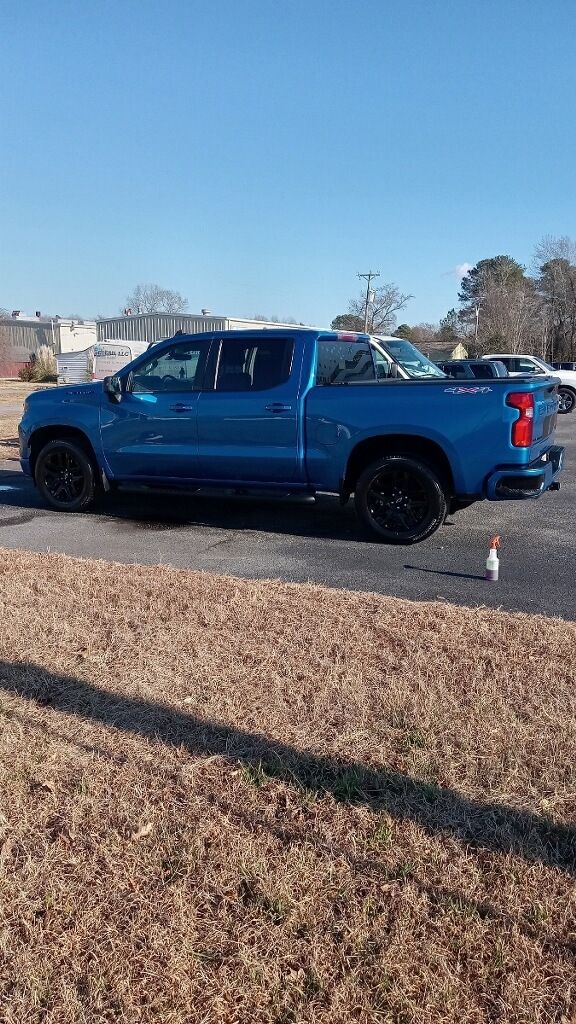 Blue Chevy Silverado pickup truck with black wheels parked outside on a sunny day.