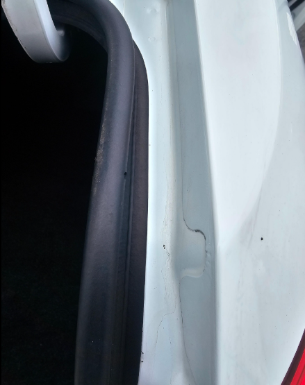 White car trunk interior with black rubber seal, showing a dark crevice.