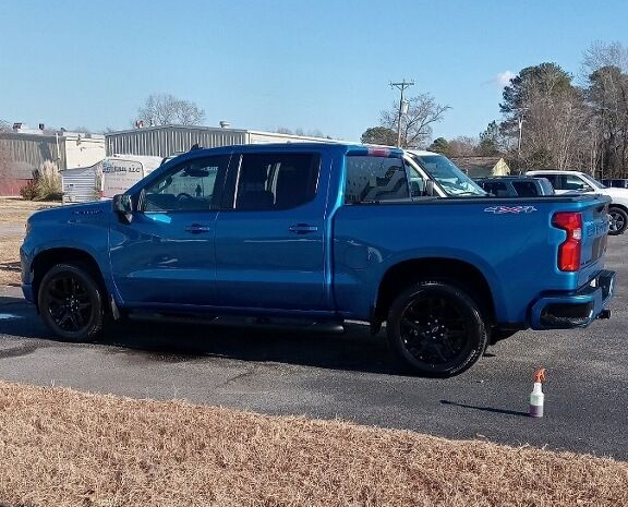 Blue Chevy Silverado pickup truck with black wheels parked outside on a sunny day.