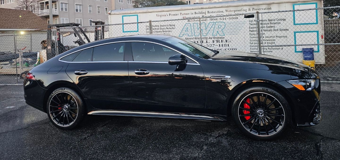 Black luxury car with red brake calipers parked near a building.