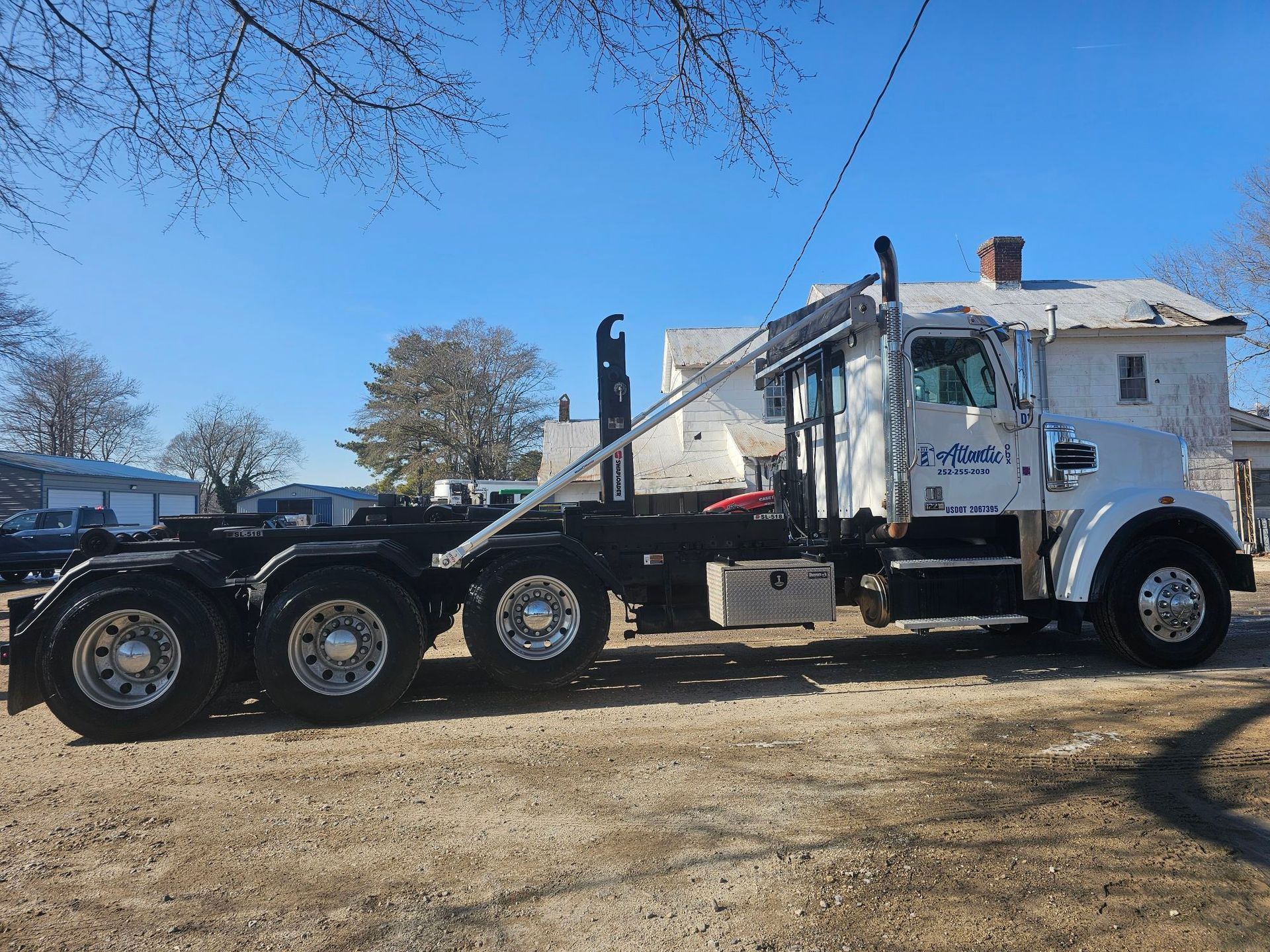 White semi-truck with a black chassis parked outside a building on a sunny day.