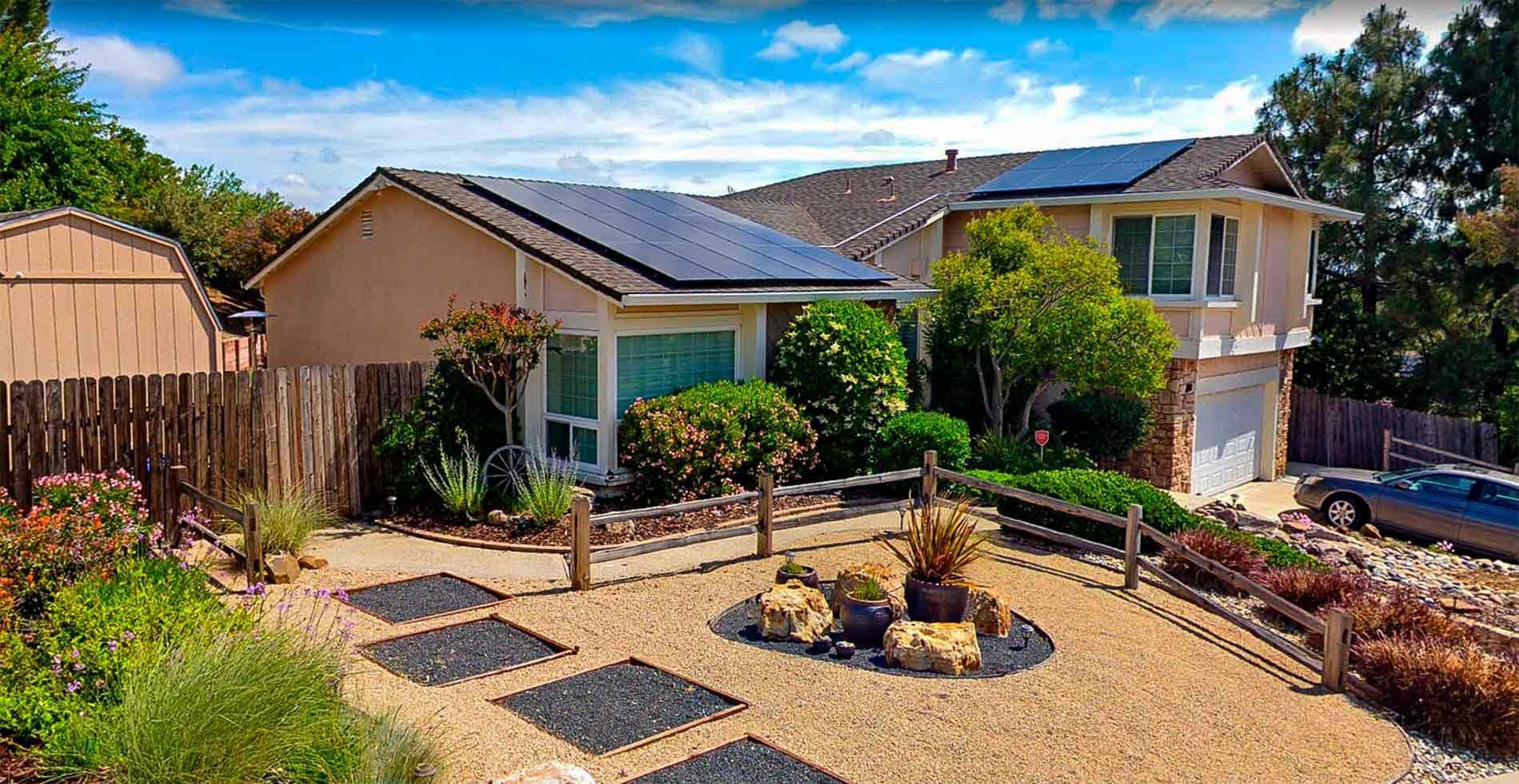 A house with solar panels on the roof and a car parked in front of it.