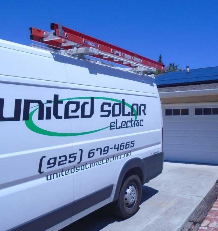 A united solar electric van is parked in front of a garage