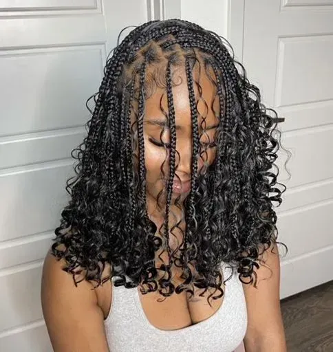 Woman with braided hairstyle, some braids framing the face, with curly ends.