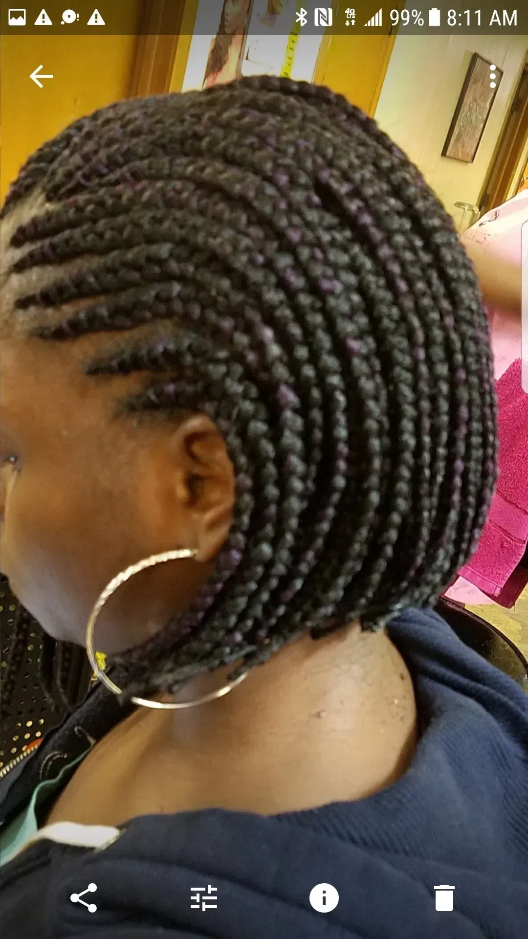 Side view of a person with braided black bob hairstyle and large gold hoop earrings.