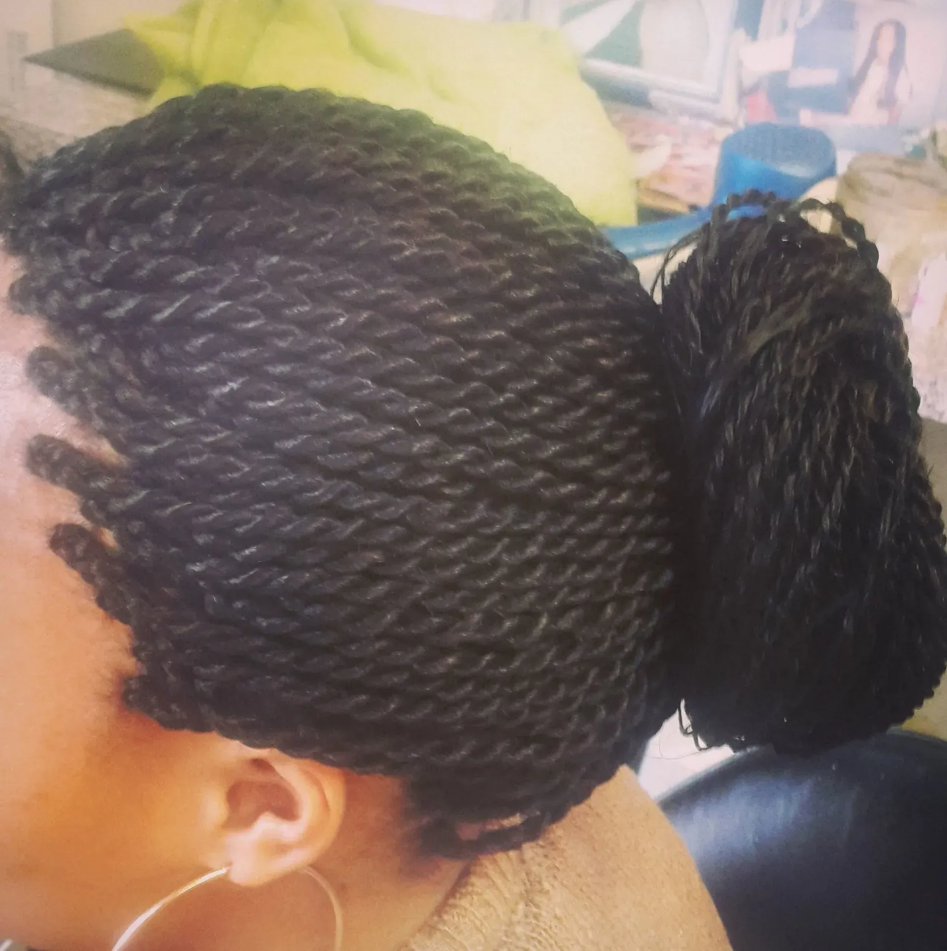 Black hair twists styled in a bun, with a loose bundle of twists next to it.