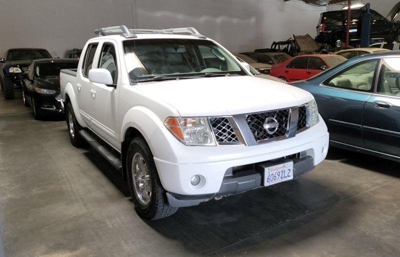 White Nissan Frontier pickup truck parked inside a garage, other vehicles in the background.