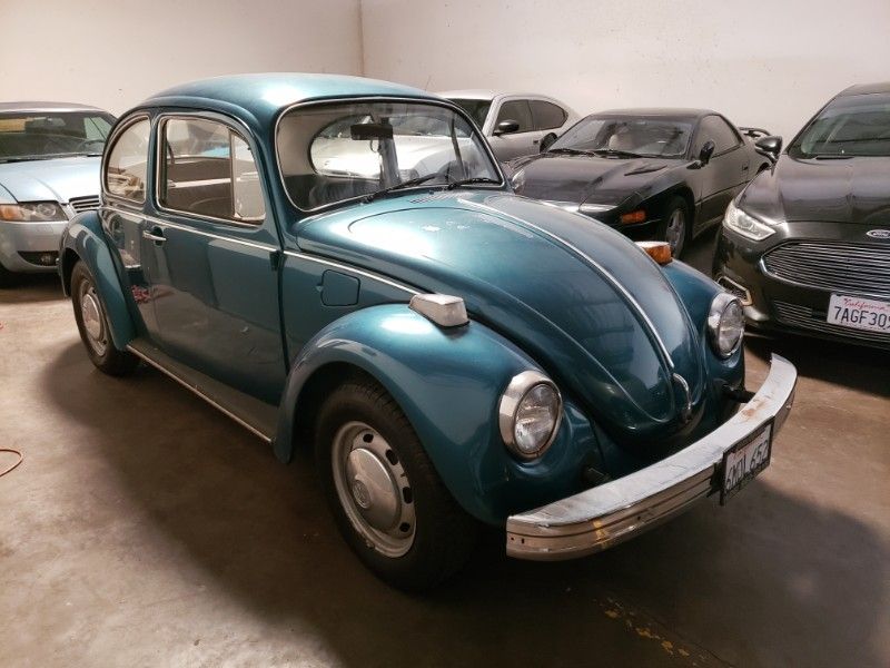 Teal vintage Volkswagen Beetle parked in a garage.