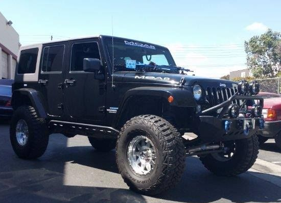 Black Jeep Wrangler with off-road modifications, large tires, and a front bumper.