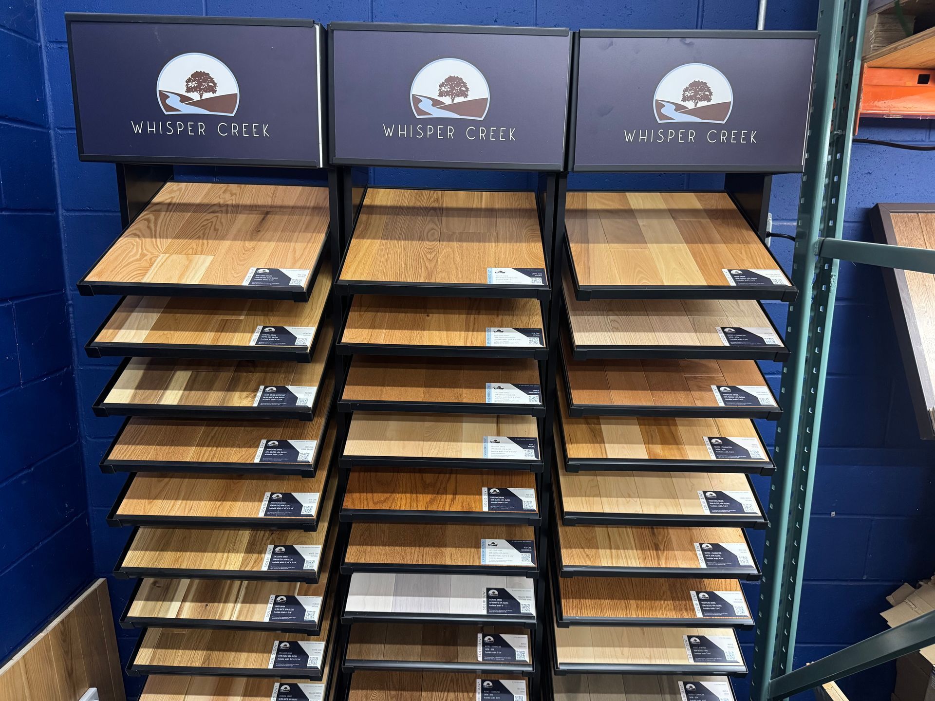 Flooring display rack featuring various wood floor samples; wood tones, blue wall background.