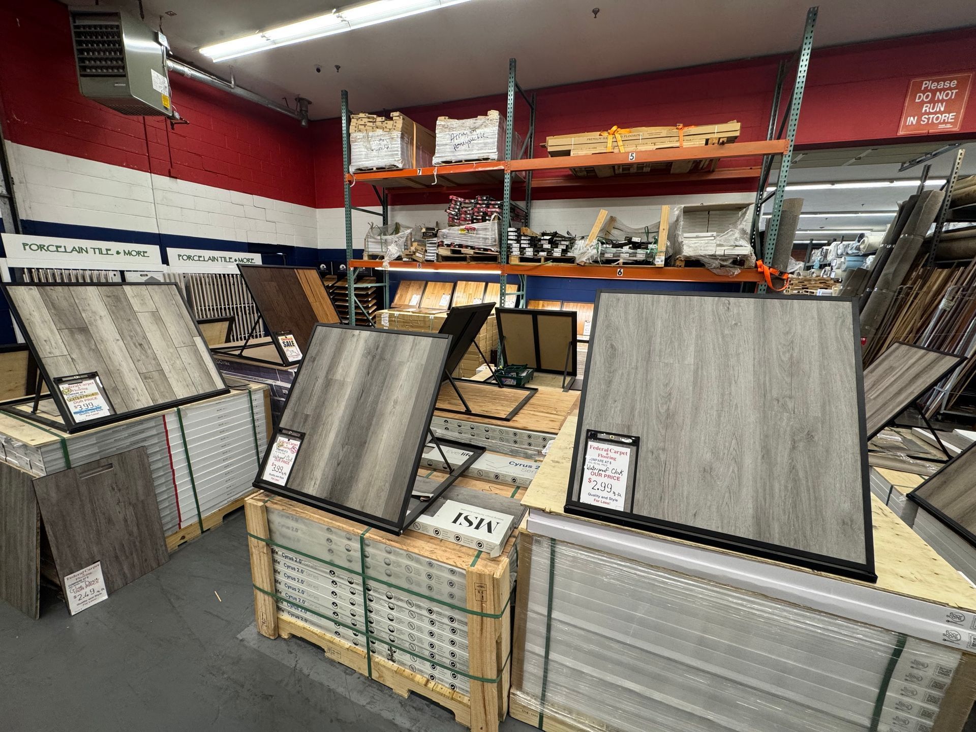 Flooring samples displayed in a warehouse, with different wood grain patterns and colors.