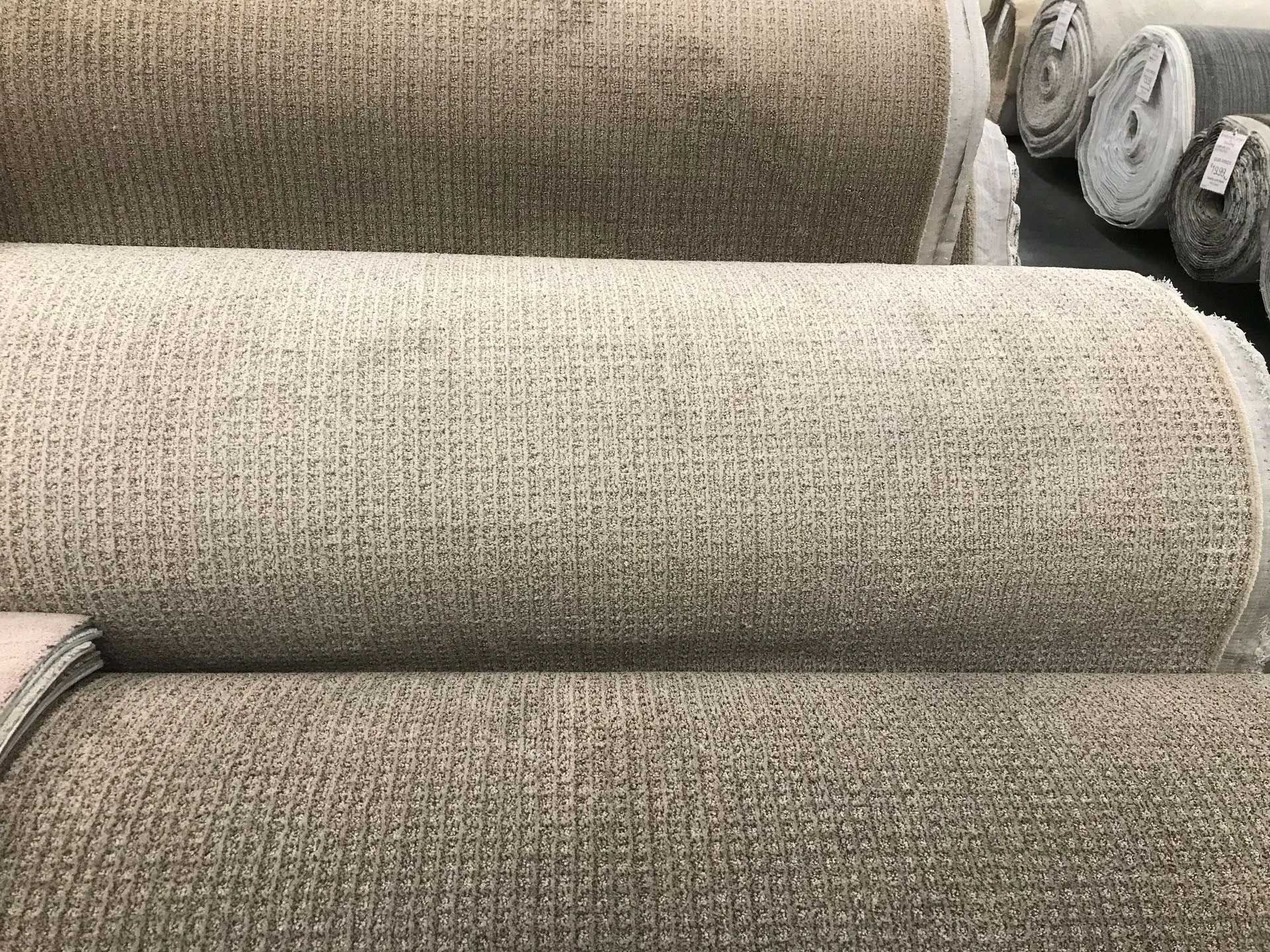 Several rolls of beige carpet fabric.