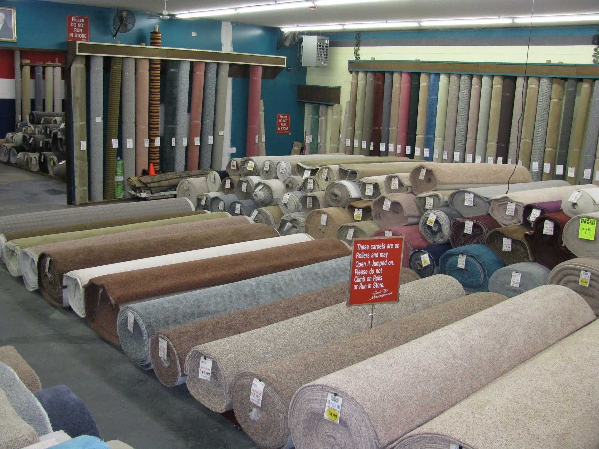 Rows of rolled carpets in various colors displayed in a store.