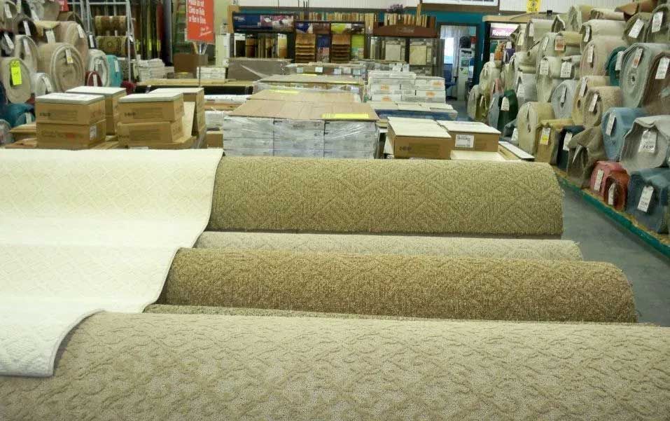 Carpeting rolls in a store, various colors and textures.